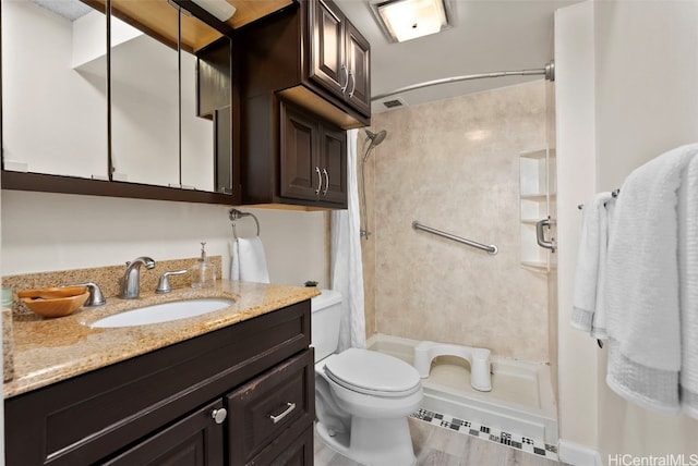 bathroom with hardwood / wood-style flooring, vanity, toilet, and walk in shower