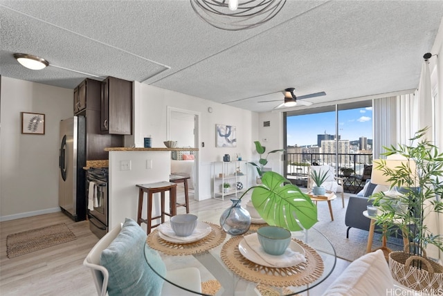 dining area with light wood finished floors, ceiling fan, a city view, and a textured ceiling