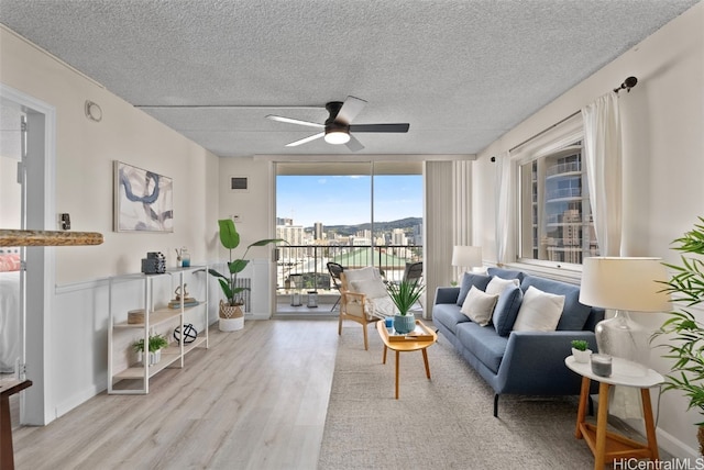 living room featuring ceiling fan, a textured ceiling, and light hardwood / wood-style flooring