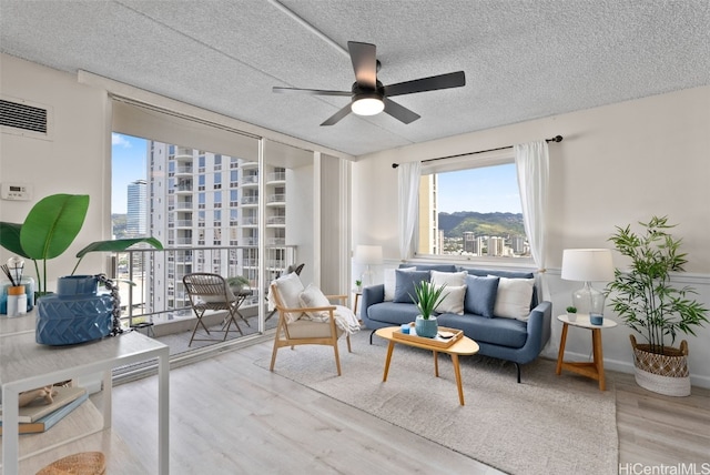 living room featuring hardwood / wood-style floors, a textured ceiling, and ceiling fan