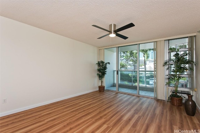 spare room with floor to ceiling windows, hardwood / wood-style floors, a textured ceiling, and ceiling fan