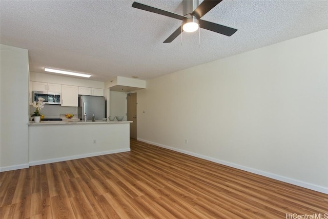 unfurnished living room with ceiling fan, a textured ceiling, and hardwood / wood-style flooring