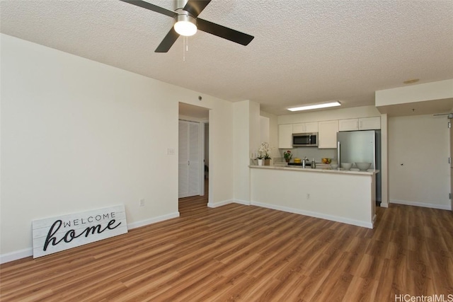 unfurnished living room featuring a textured ceiling, dark hardwood / wood-style floors, ceiling fan, and sink