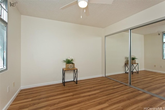 unfurnished bedroom featuring multiple windows, a closet, and hardwood / wood-style flooring