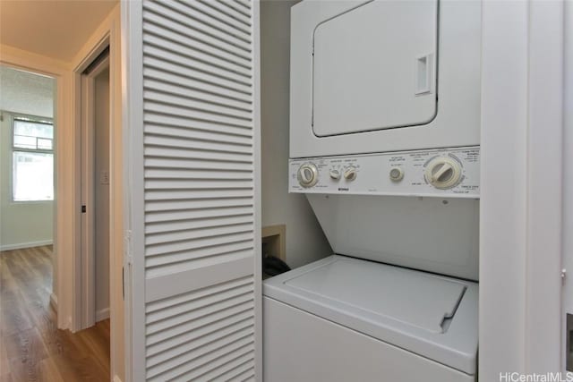 laundry room with light hardwood / wood-style flooring and stacked washer and clothes dryer