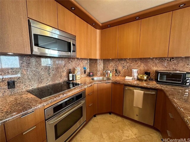 kitchen featuring sink, stainless steel appliances, dark stone counters, and tasteful backsplash