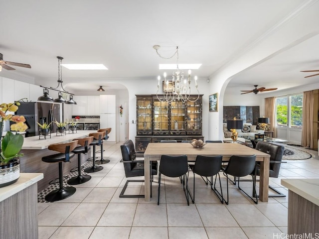 tiled dining space featuring ceiling fan with notable chandelier and ornamental molding