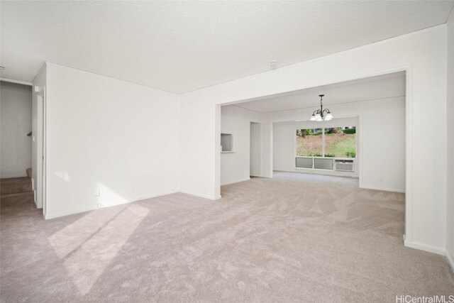 unfurnished living room with light carpet, a chandelier, and a textured ceiling