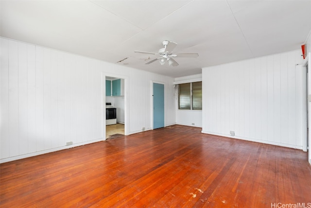 empty room featuring hardwood / wood-style floors, ceiling fan, and wooden walls