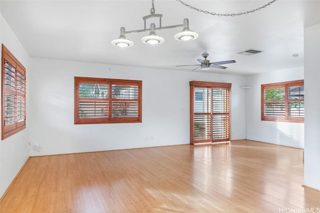 empty room featuring ceiling fan, a healthy amount of sunlight, and light wood-type flooring