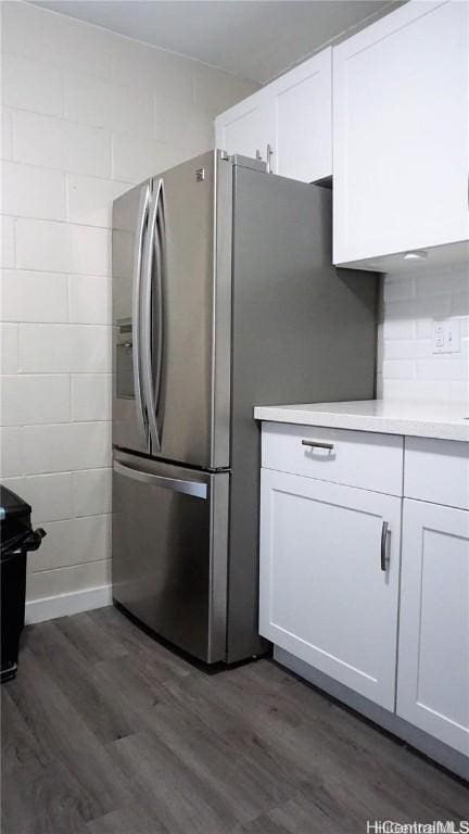 kitchen featuring stainless steel fridge, dark hardwood / wood-style flooring, and white cabinetry