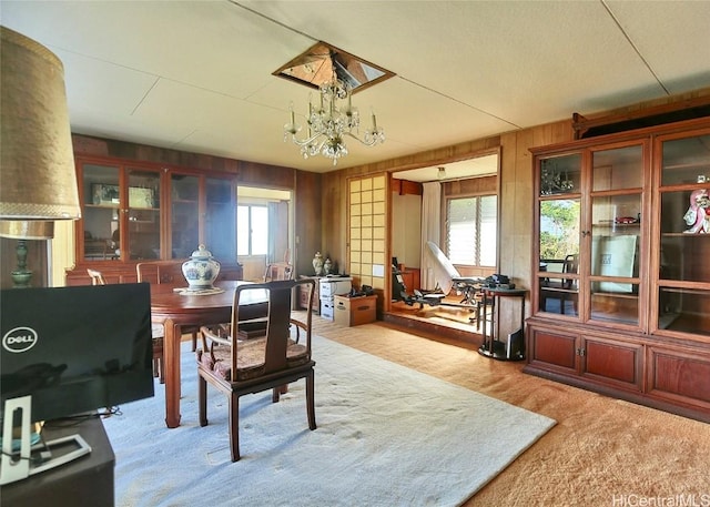 dining space featuring a notable chandelier, wood walls, light carpet, and a wealth of natural light