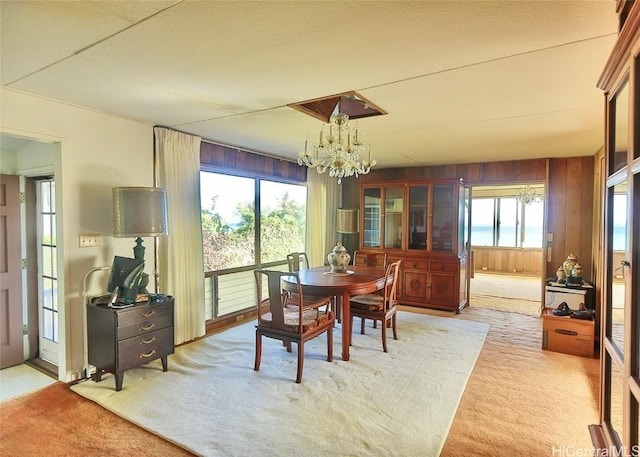 dining room with wooden walls, light colored carpet, and a healthy amount of sunlight