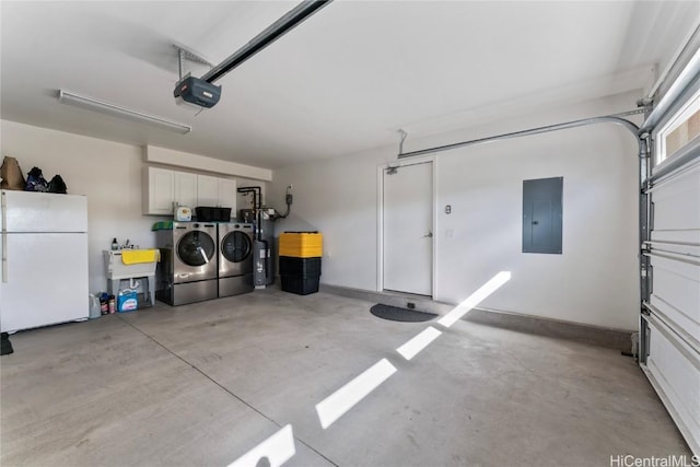 garage featuring electric water heater, white refrigerator, washing machine and clothes dryer, electric panel, and a garage door opener