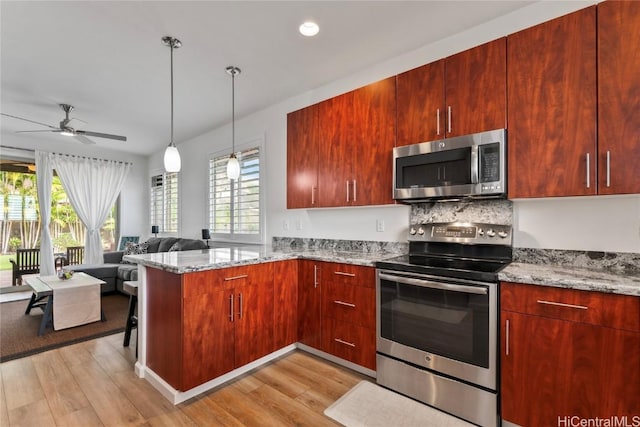 kitchen featuring ceiling fan, light stone countertops, light wood-type flooring, appliances with stainless steel finishes, and kitchen peninsula