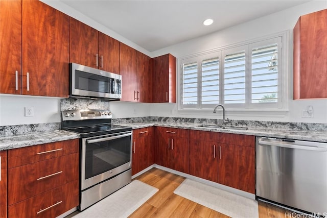 kitchen featuring sink, light hardwood / wood-style flooring, light stone countertops, and appliances with stainless steel finishes