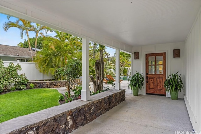 view of exterior entry featuring a lawn and a porch