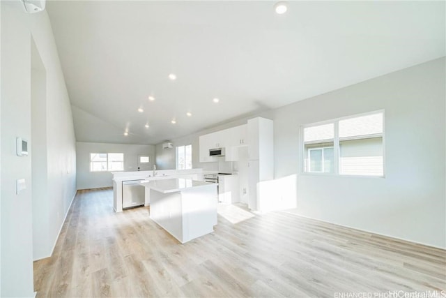 kitchen featuring electric range, light wood-style flooring, stainless steel dishwasher, white cabinets, and a kitchen island