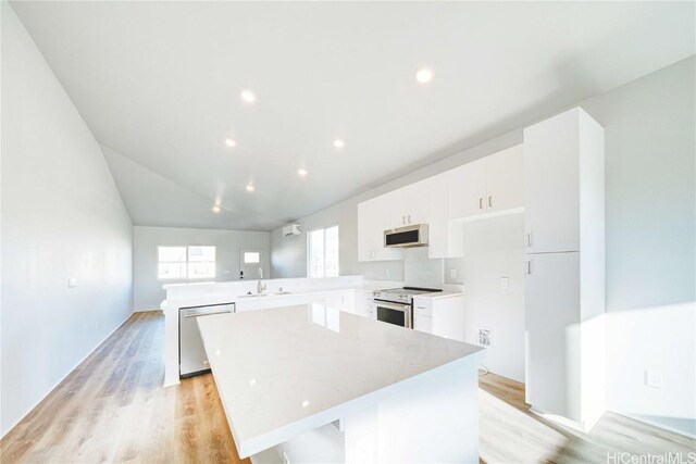 kitchen featuring kitchen peninsula, stainless steel appliances, sink, light hardwood / wood-style flooring, and a kitchen island