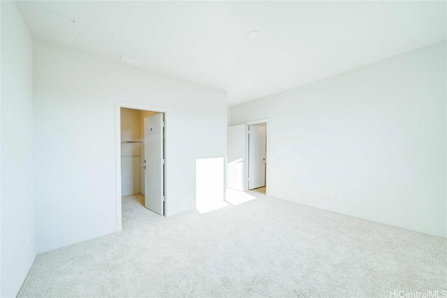 unfurnished bedroom with light carpet, a walk in closet, and a closet