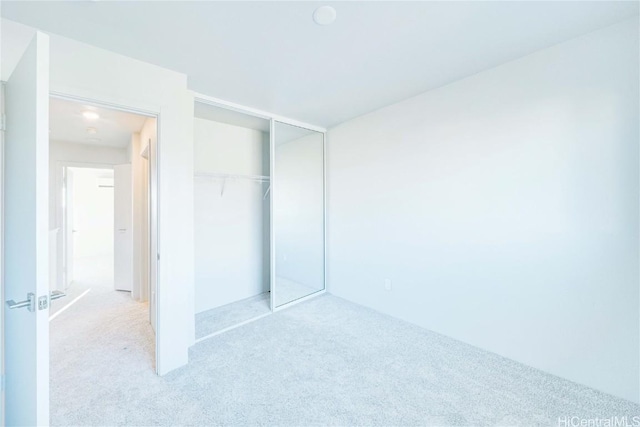 unfurnished bedroom with light carpet and a closet