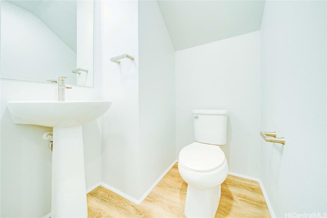 bathroom with hardwood / wood-style floors, toilet, and vaulted ceiling