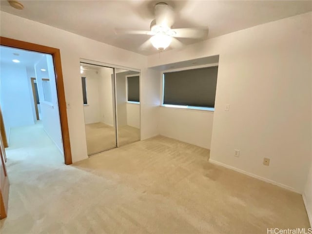 unfurnished bedroom with ceiling fan, a closet, and light colored carpet