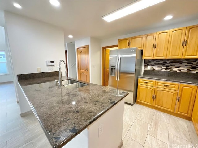 kitchen with decorative backsplash, stainless steel fridge with ice dispenser, dark stone counters, and sink