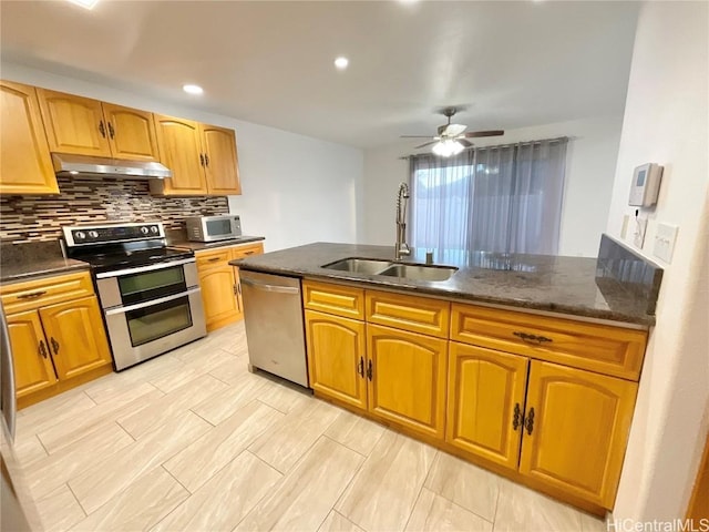 kitchen with backsplash, dark stone counters, sink, ceiling fan, and appliances with stainless steel finishes