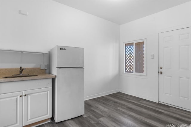 kitchen with white fridge, dark hardwood / wood-style flooring, white cabinetry, and sink