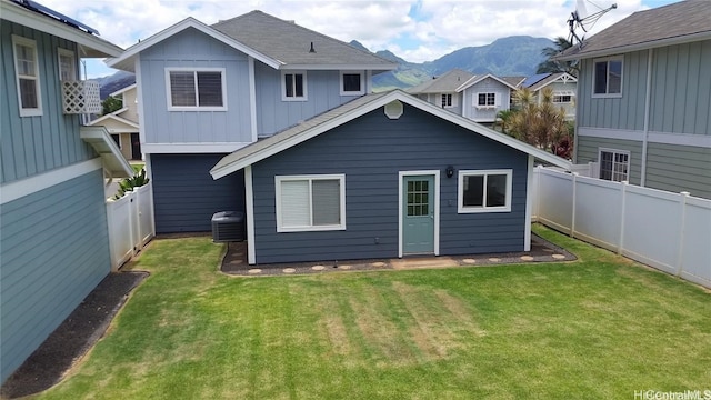 back of house with a mountain view, a yard, and central AC unit