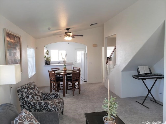 carpeted dining space with ceiling fan and lofted ceiling