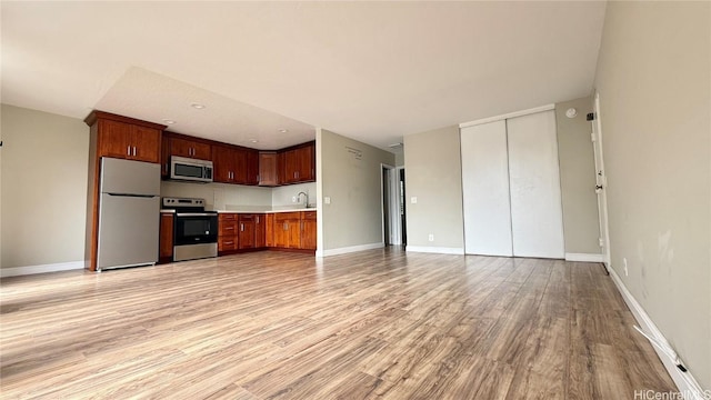 kitchen with appliances with stainless steel finishes and light hardwood / wood-style floors