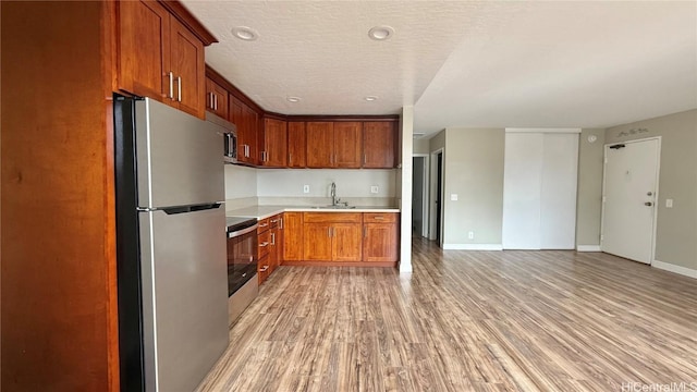 kitchen featuring a textured ceiling, light hardwood / wood-style floors, sink, and appliances with stainless steel finishes