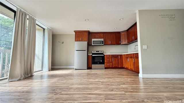 kitchen with light hardwood / wood-style floors and appliances with stainless steel finishes