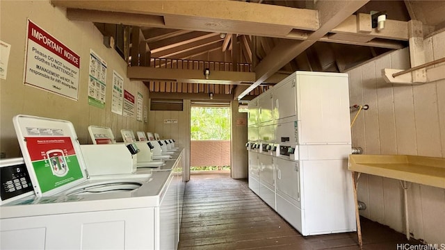 washroom featuring wooden walls, washer and clothes dryer, dark hardwood / wood-style floors, and stacked washer and clothes dryer