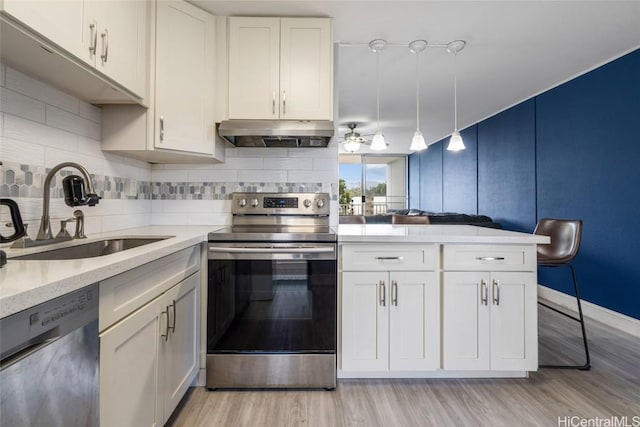 kitchen with pendant lighting, white cabinets, sink, kitchen peninsula, and stainless steel appliances