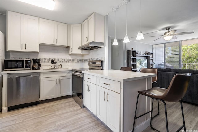 95-2031 Waikalani Pl Unit D906, Mililani, HI 96789 - kitchen featuring appliances with stainless steel finishes, under cabinet range hood, a kitchen bar, light countertops, and decorative backsplash