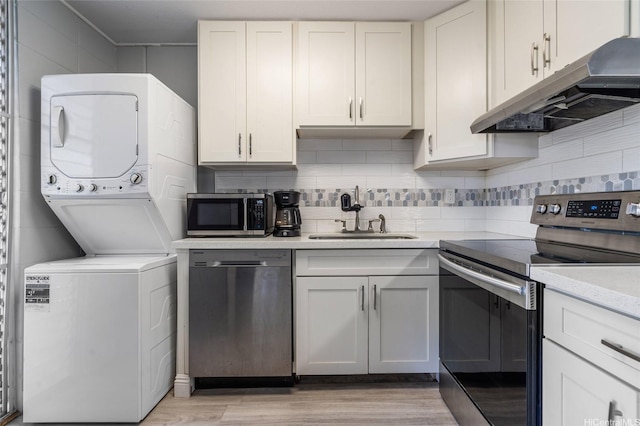 95-2031 Waikalani Pl Unit D906, Mililani, HI 96789 - kitchen featuring appliances with stainless steel finishes, under cabinet range hood, stacked washing machine and dryer, light countertops, and light wood finished floors