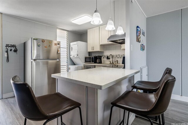 95-2031 Waikalani Pl Unit D906, Mililani, HI 96789 - kitchen with appliances with stainless steel finishes, estacked washer and dryer, a kitchen breakfast bar, and light wood finished floors