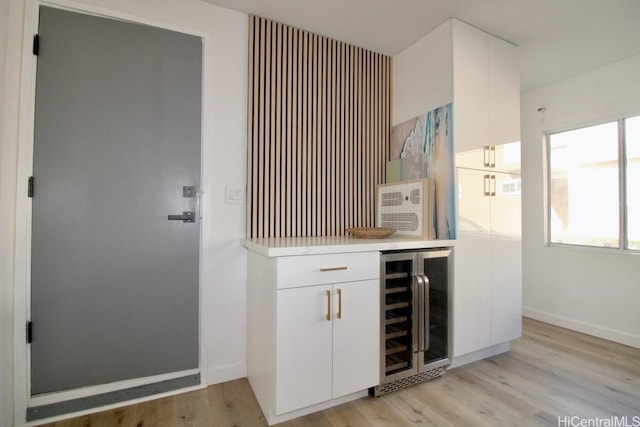 bar featuring white cabinets, light hardwood / wood-style flooring, and beverage cooler