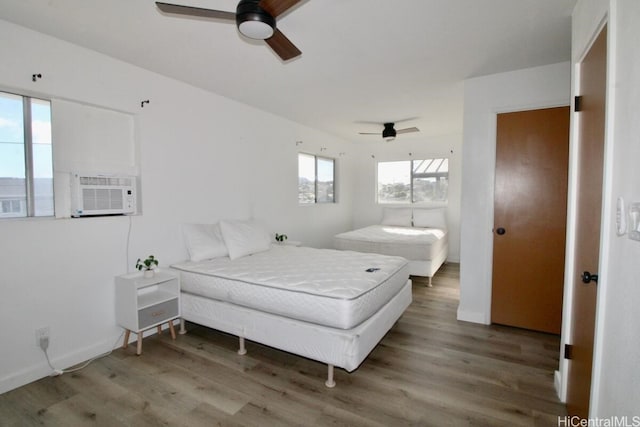 bedroom featuring hardwood / wood-style flooring, ceiling fan, and cooling unit