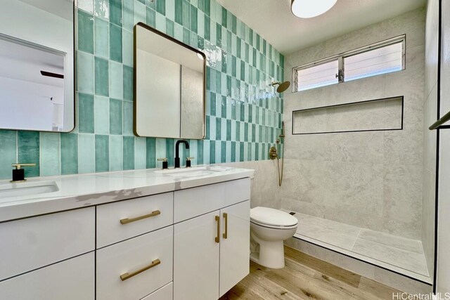 bathroom with vanity, toilet, wood-type flooring, and tile walls