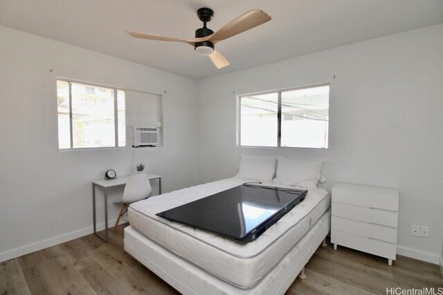 bedroom with ceiling fan, cooling unit, and wood-type flooring