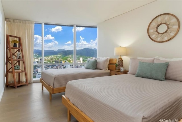 bedroom with hardwood / wood-style floors, a mountain view, and expansive windows