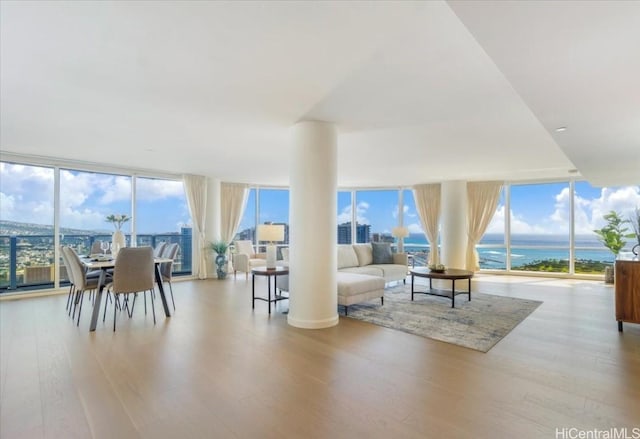 living room with a water view, expansive windows, and light wood-type flooring