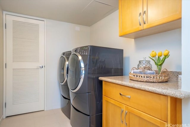 laundry area featuring washer and dryer, cabinets, and light tile patterned floors