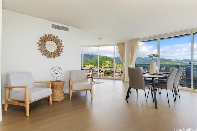 dining area with a wall of windows, a mountain view, and hardwood / wood-style flooring