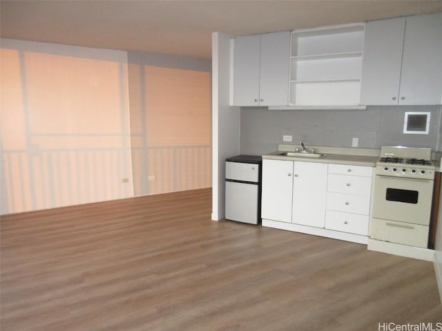 kitchen with tasteful backsplash, white appliances, sink, white cabinets, and hardwood / wood-style floors