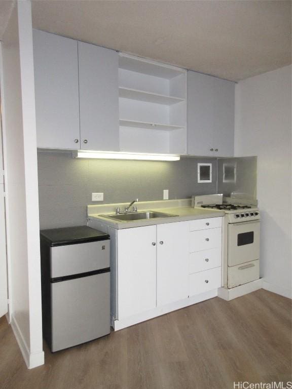 kitchen with white cabinets, wood-type flooring, white gas range, and sink